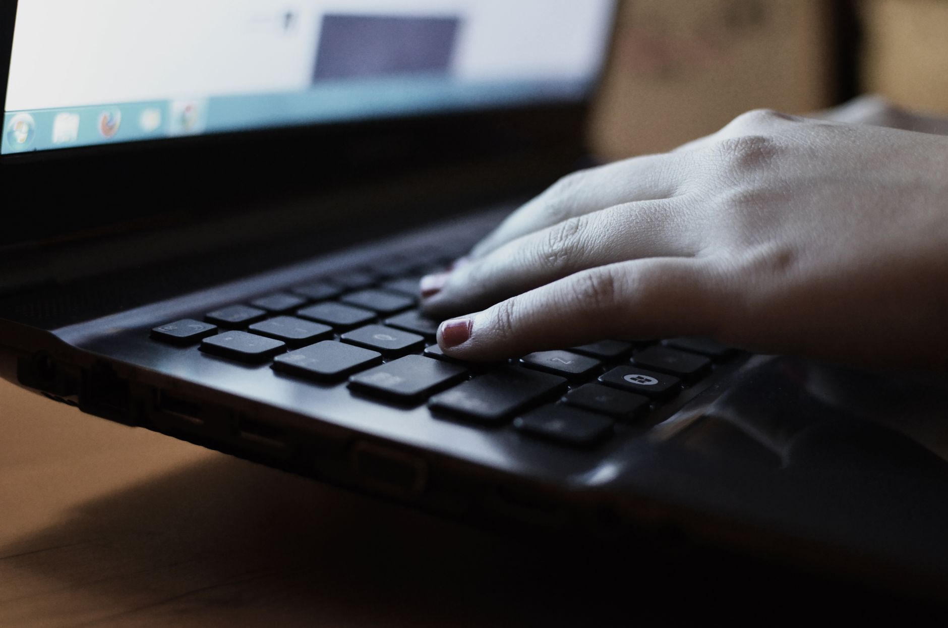 Zbliżenie dłoni piszących na klawiaturze laptopa we wnętrzu.